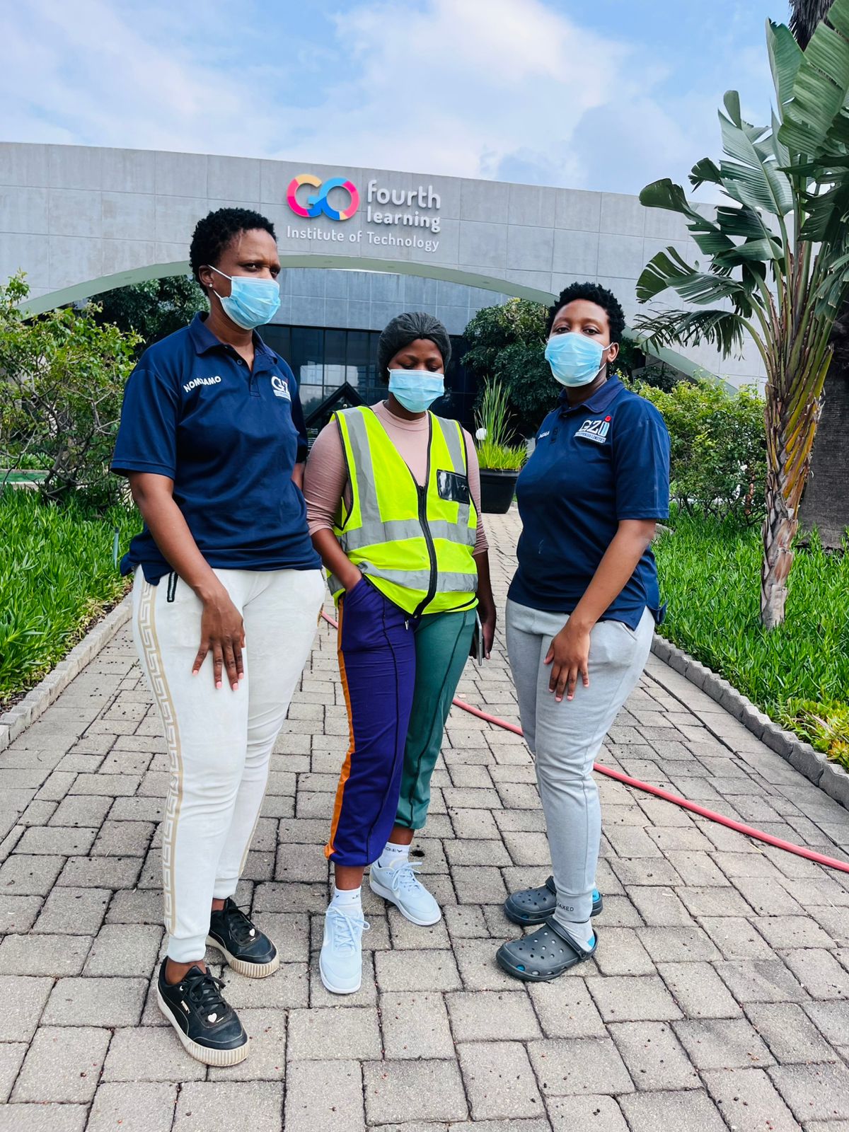 Three workers in uniform and vests posing outdoors